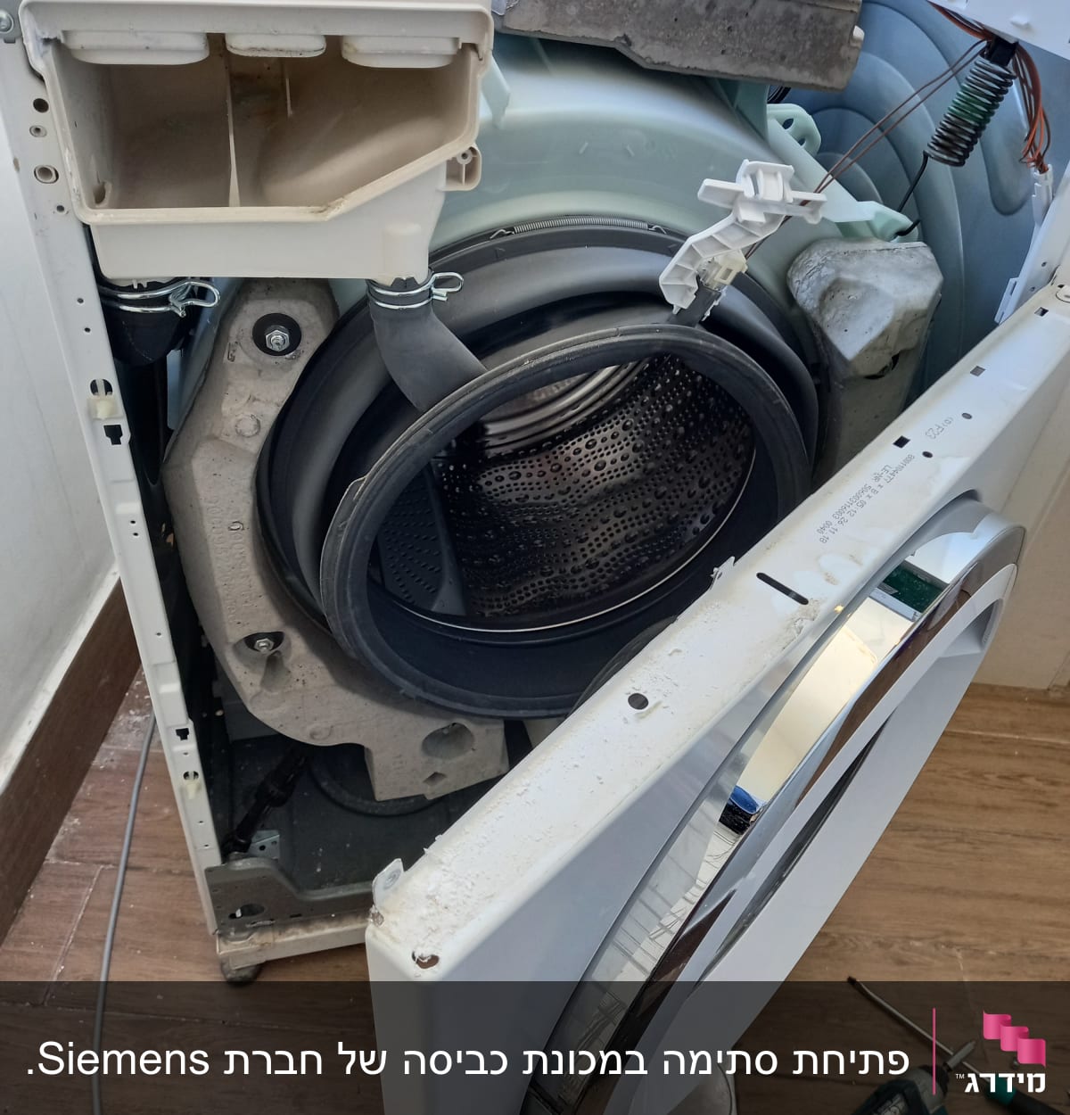 מכונת כביסה פתוחה עם חלקים חשופים וכלי עבודה